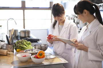 野菜を手に取り笑顔で会話する女性検査員たち