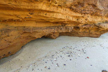Brown eroded rock formations against sandy beach. Melbourne, VIC Australia