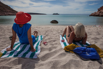 Two women relaxing on beach towels looking at the ocean