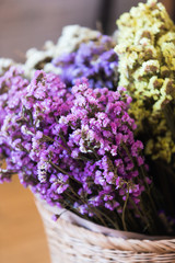 Purple and yellow flowers are in a wooden vase