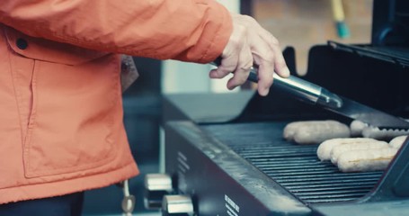 Senior man cooking sausages on barbecue