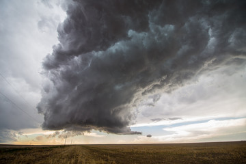 A supercell thunderstorm towers over the landscape of the Great Plains.
