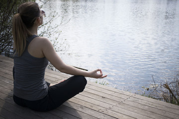 Young girl practices yoga on the shore of the lake, the concept of enjoying privacy and concentration, sunlight