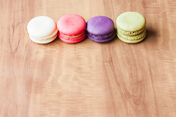 Colorful French Macarons on wooden background.