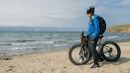 Fototapeta premium Fat bike also called fatbike or fat-tire bike in summer driving on the beach. The guy is going straight on the beach. On the sand on such a bike ride is not difficult.