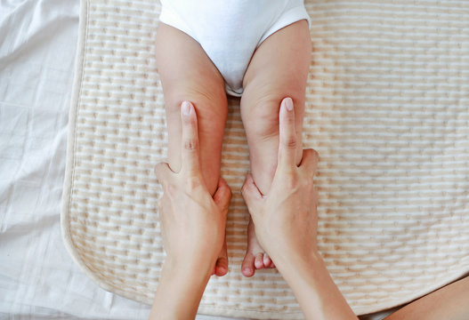Mother hand massaging to leg of infant baby.