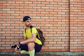 A man in sportswear with a backpack against a brick wall background.
