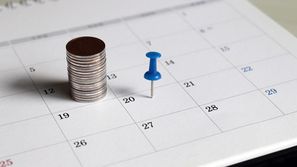 A pile of coins and a blue tack on the calendar.