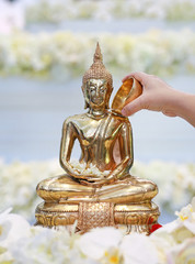 Water blessing ceremony for Songkran Festival or Thai New Year. People paying respects to a statue of Buddha by pouring water onto it. © zilvergolf