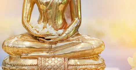 Poster Bouddha Gros plan d& 39 une statue de Bouddha en or avec une fleur de jasmin sur les mains.