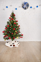 Blue and silver balls and wreath on white brick wall holiday background with christmas tree