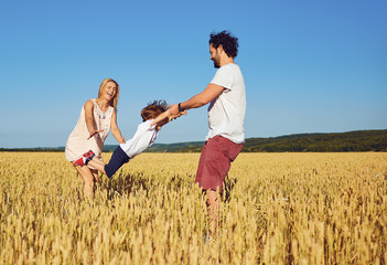 A happy family is enjoying fun with a child outdoors in a summer field.