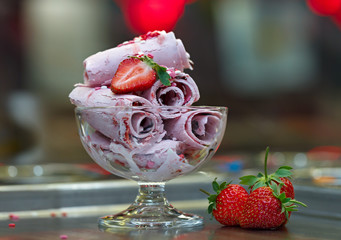 Roll ice cream is made by hand on the freezer. Sweet dessert made from natural strawberries and...