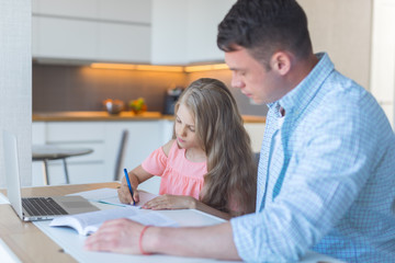 Young dad with a little daughter doing homework