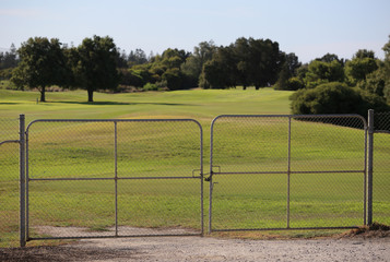 Golf course. The entrance to the private area is closed. Private property no entry. Steel gates. Green field.