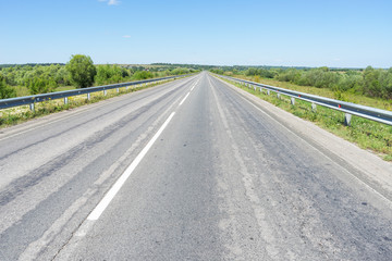 Obraz premium Vanishing straight highway with metal rails along. Kozelsk, Kaluzhsky region, Russia.