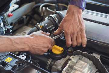 Auto mechanic hands with wrench repairing car. Selective focus.