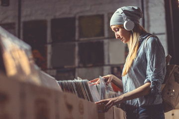 Young woman with headphones browsing vinyl records