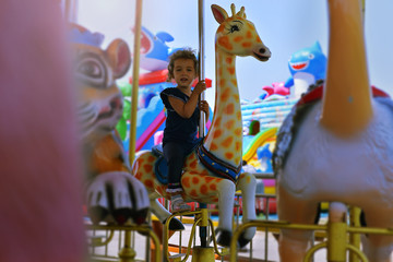 Child on the carousel. Little girl on the carousel. Children attractions
