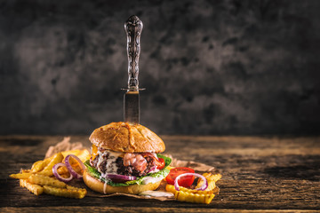 Close-up home made beef burger with knife and fries on wooden table