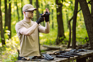 guy in the woods tests his weapons for shooting sports