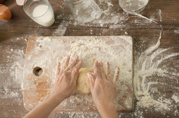 Woman kneading dough for bakery on kitchen table
