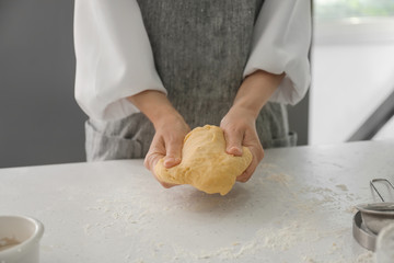 Woman kneading dough for bakery on kitchen table