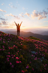 Hiker woman standing with hands up achieving the top. Girl welcomes a sun. Successful woman hiker...