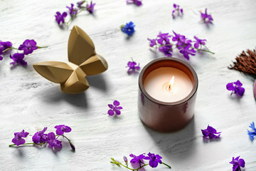 Fototapeta na wymiar Burning candle and beautiful flowers on white wooden table