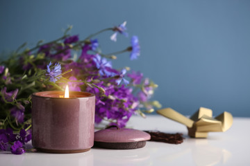 Burning candle and beautiful flowers on white table