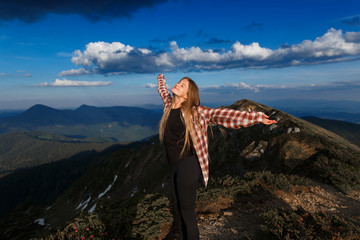 Hiker woman standing with hands up achieving the top. Girl welcomes a sun. Conceptual design. Successful woman hiker open arms on sunrise mountain top. Happy young blonde woman portrait