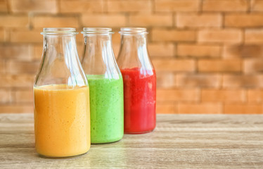 Bottles with fresh tasty smoothies on wooden table