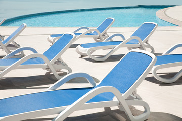 Obraz premium Many blue chaise lounge by the pool.