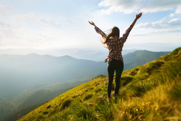 Hiker woman standing with hands up achieving the top. Girl welcomes a sun. Conceptual design. Successful woman hiker open arms on sunrise mountain top. Happy young blonde woman portrait - 210272884