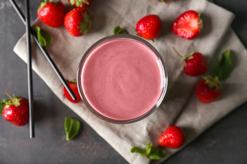 Glass with tasty strawberry smoothie on grey table