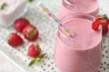 Glass with tasty strawberry smoothie on table, closeup