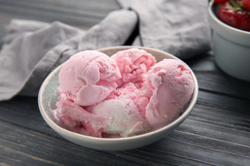 Bowl with tasty strawberry ice cream on wooden table