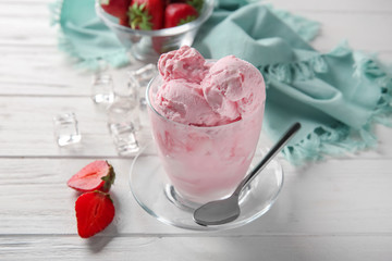 Glass with tasty strawberry ice cream on wooden table