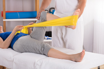 Physiotherapist Giving Leg Treatment With Exercise Band