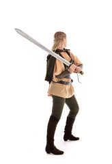 full length portrait of girl wearing medieval costume with sword. standing pose with back to the camera, isolated on white studio background.