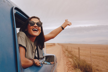 Excited woman out on a road trip in car