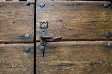old wooden door with metal studs and snake-shaped handle