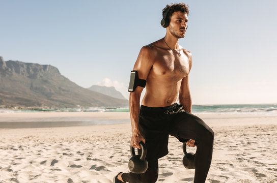 Fototapeta Man doing fitness training at the beach with kettlebells