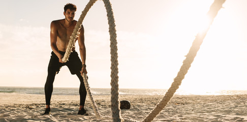 Man doing workout using battling ropes at the beach © Jacob Lund