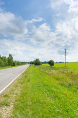 Fototapeta na wymiar Vanishing straight highway with sunny meadow along 