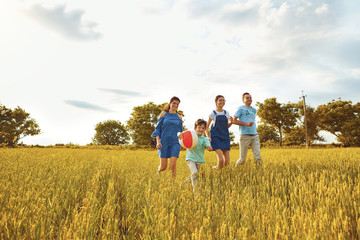 Happy family smiling running on the field in nature.
