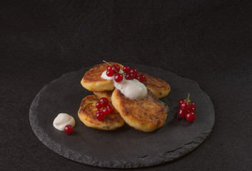 cheese cupcakes, fritters, syrniki served with berries on black shale 