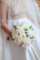 Beautiful wedding bouquet in bride's hand of white peonies