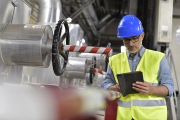 Industrial technician connected with tablet in recyling plant - obrazy, fototapety, plakaty
