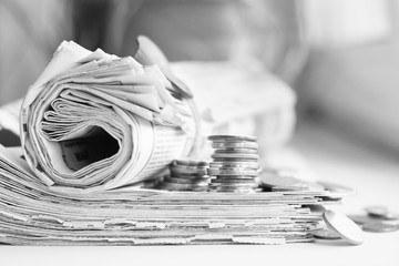 Pile of newspapers and money. Daily papers with news folded and rolled, stack of coins on table. Journals and lots of change, side view     